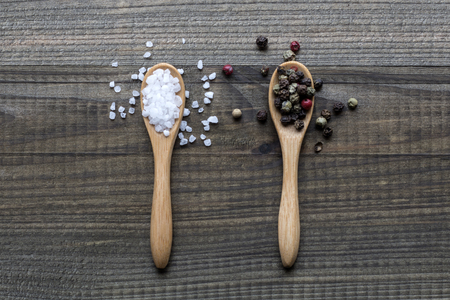 salt and pepper on wooden spoonsの写真素材