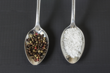 Salt and pepper on metal spoonsの写真素材