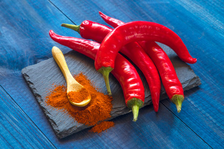Red hot chili peppers and paprika powder on a blue wooden backgroundの写真素材