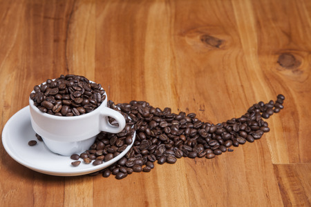 coffee beans in a cup on the wooden tableの写真素材