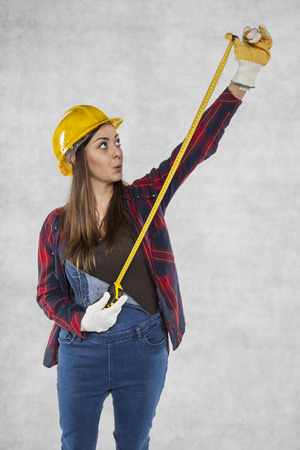 Woman builder stretches a meter, surprised faceの写真素材