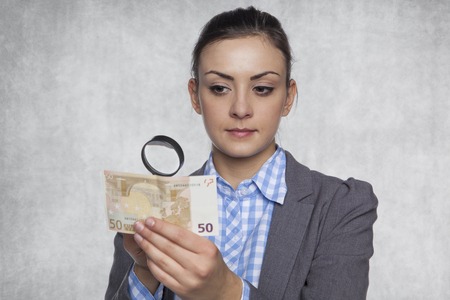 Young business woman checks the authenticity of moneyの写真素材