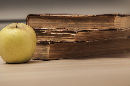 Books and an apple lie on the tableの写真素材