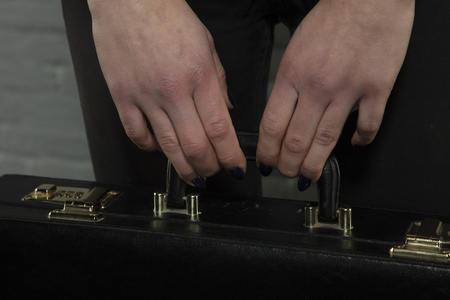 Close-up of a secretary's hands holding a briefcase