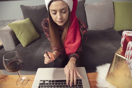 lonely girl in a Christmas hat shopping online, front viewの写真素材
