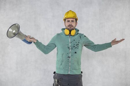the construction worker holds a megaphone in his hands, the concept of issuing ordersの写真素材