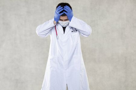 a doctor in protective clothing grabs his head