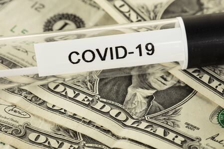 coronavirus tests lie on a one dollar bill, the symbolism of a pandemic and the costs associated with itの写真素材