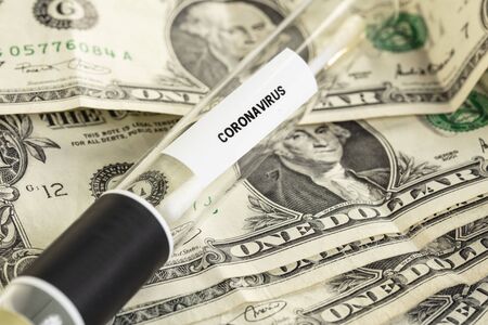 coronavirus tests lie on a one dollar bill, the symbolism of a pandemic and the costs associated with itの写真素材