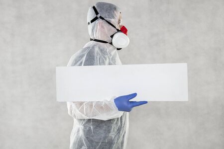 virologist in protective clothing holds advertising space in his handsの写真素材