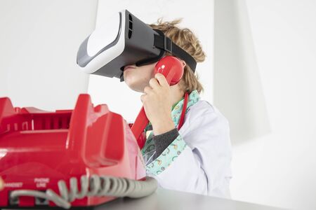 young doctor in virtual reality goggles talking on the phone, a symbol of globalizationの写真素材