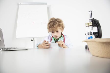 young doctor uses the phone, sitting in his officeの写真素材