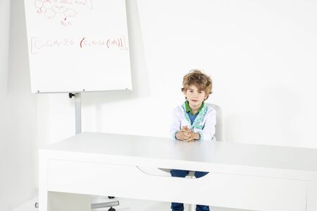 young doctor is sitting behind the desk in his doctor's office