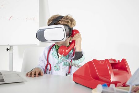 young doctor in virtual reality goggles talking on the phone, a symbol of globalizationの写真素材