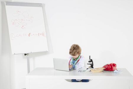 young doctor works on the computer, sits at a desk in his officeの写真素材