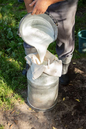farmer passes the milk through the strainer, the old way of cleaning milk from dirtの写真素材