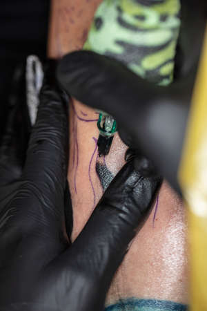 close-up on the tattoo machine while doing a tattooの写真素材