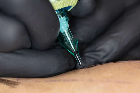 close-up on the tattoo machine while doing a tattooの写真素材