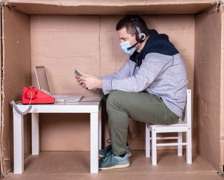 employee works from his own cardboard office to isolate himself from othersの写真素材