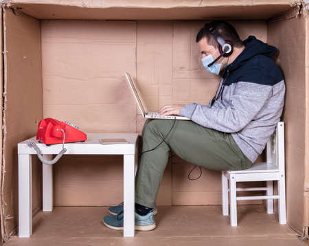 employee works from his own cardboard office to isolate himself from othersの写真素材