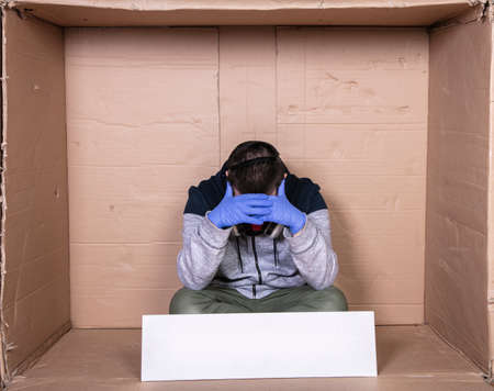 man in the protective mask sits in a cardboard box, he is totally burned out