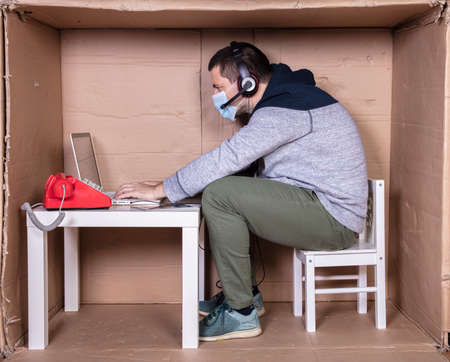 employee works from his own cardboard office to isolate himself from othersの写真素材