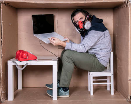 employee works from his own cardboard office to isolate himself from othersの写真素材