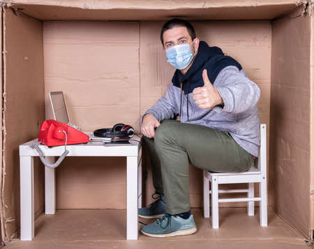 employee works from his own cardboard office to isolate himself from othersの写真素材