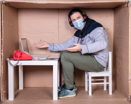 employee works from his own cardboard office to isolate himself from othersの写真素材