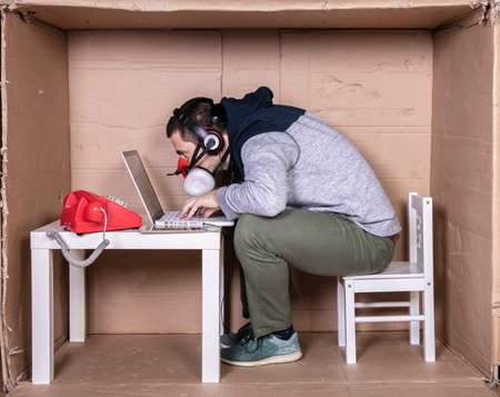 employee works from his own cardboard office to isolate himself from othersの写真素材