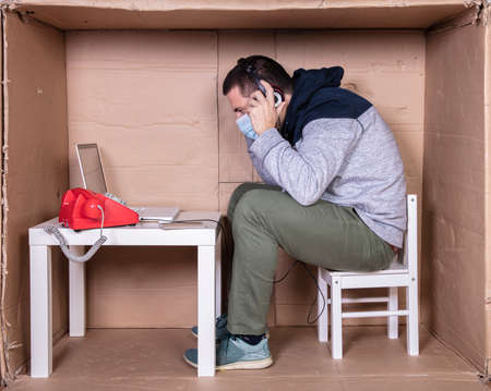 employee works from his own cardboard office to isolate himself from othersの写真素材