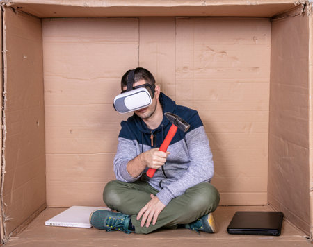 unemployed boy wearing VR glasses with a hammer in his handの写真素材