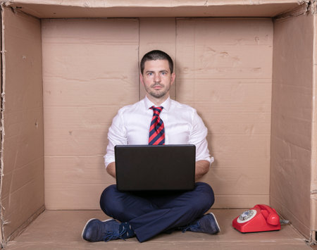 businessman with full concentration works on his laptop, a tight office is not a problemの写真素材