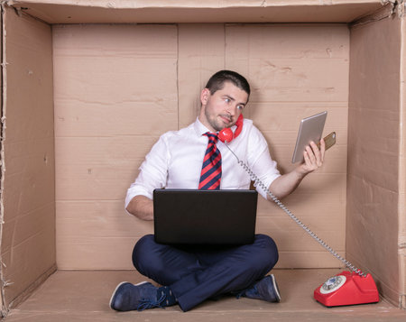 businessman talking on the phone, looks at multimedia devicesの写真素材