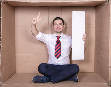 businessman shows a victory symbol, holds copy space in other handの写真素材