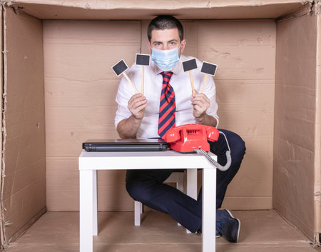 dissatisfied businessman with facial mask holds the placard in his hands, copy spaceの写真素材