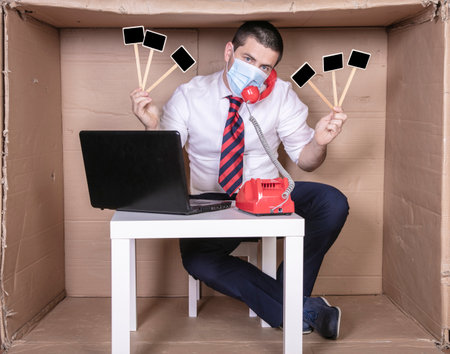 businessman is on a phone call, protective mask on his face and placard with copy space in handの写真素材