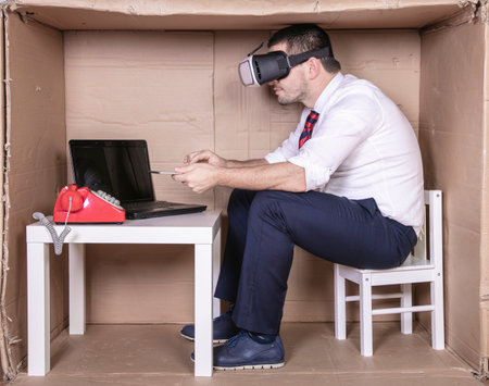 businessman in a cardboard office working with high technologyの写真素材