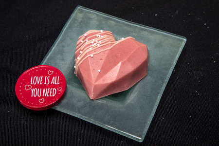 beautiful chocolate heart-shaped cupcake lies on a glass saucer, isolated on a black backgroundの写真素材