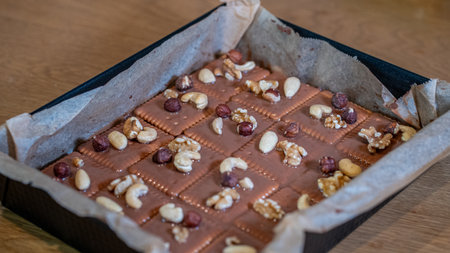 Homemade chocolate with nuts and raisins on a wooden tableの写真素材