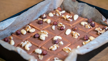 chocolate with nuts and raisins in a baking sheet on a wooden tableの写真素材