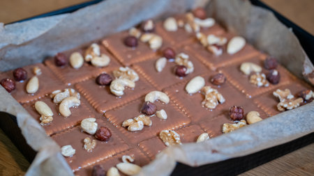 Homemade chocolate bar with nuts and raisins on wooden tableの写真素材