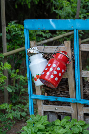 Ceramic milk cans on a wooden shelf in the garden.の写真素材