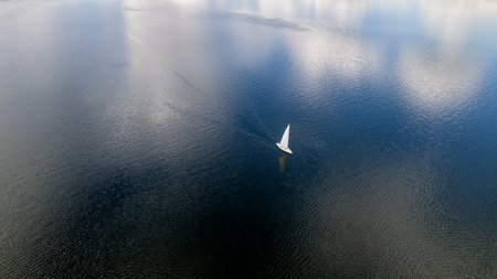 Aerial view of a sailboat sailing on the blue water.の写真素材