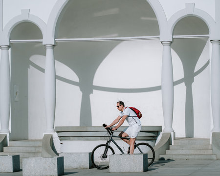 stylish man in sunglasses riding bicycle on stairs near arch in cityの写真素材
