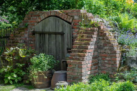 Old wooden door of a country house with a brick wall in the gardenの写真素材