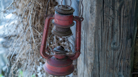 Old rusty kerosene lamp hanging on a rustic wooden poleの写真素材