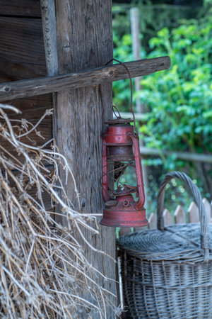 Old red lamp hanging on the wall of a rustic country houseの写真素材