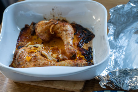 Baked chicken wings with carrots and onions in white bowl on wooden tableの写真素材