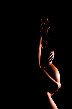 Naked pregnant woman covering her breastの写真素材